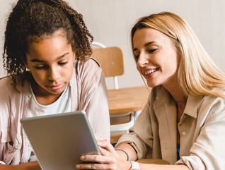 Teacher working with student on tablet in classroom with wi-fi
