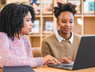 Teacher helping student in K–12 with laptop