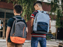 Two boys approach a school wearing backpacks