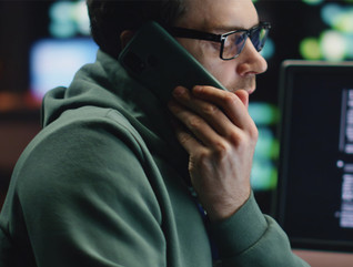 Man talking on cell phone surrounded by computers and data