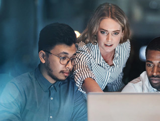 Three people looking at a laptop screen.