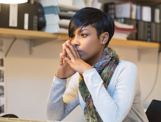 IT person mulling over information while sitting at desktop computer