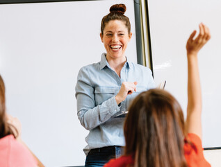A teacher in the front of a classroom teaching students.