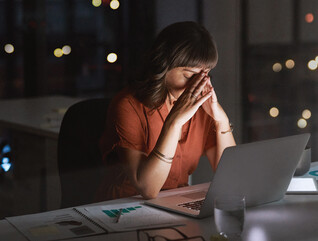 Woman sitting in front of a laptop looking concerned late at night