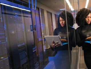 IT leader using a laptop computer next to servers