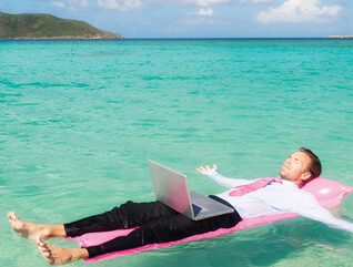 Person floating in the ocean while working on a computer