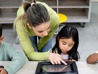 Teacher helping students using tablets