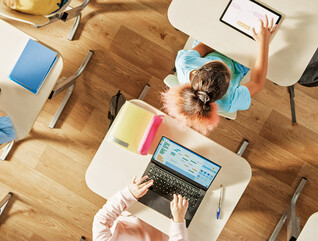 Overhead view of children sitting at desks working in a classroom on computers