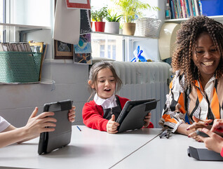 Teacher helping students using tablets