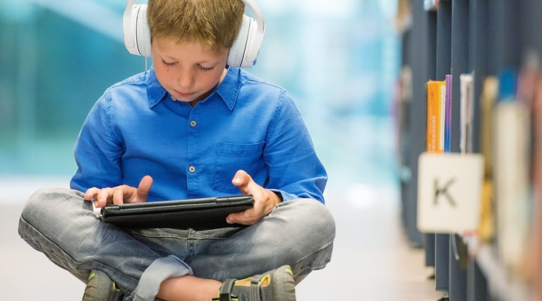 Child on tablet in a library