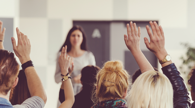 Teachers raising their hands in a training seminar
