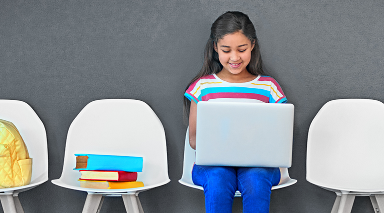 girl in row of chairs on laptop