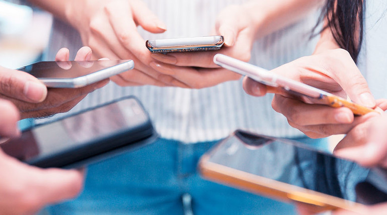 Group of people holding their smartphone and testing a mobile app.