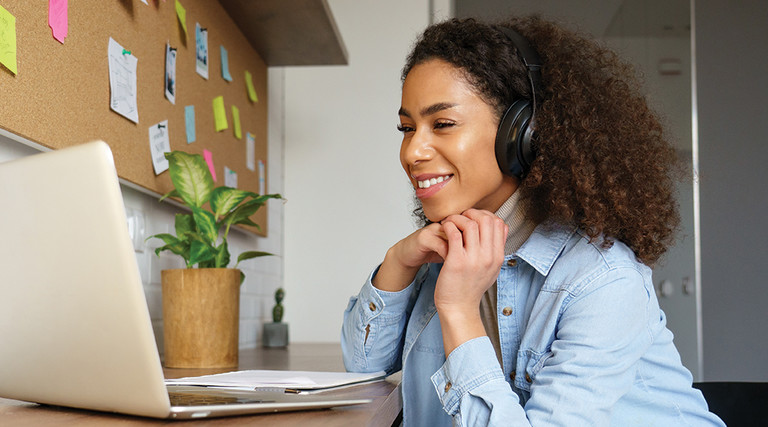 woman with headphones looking at a laptop