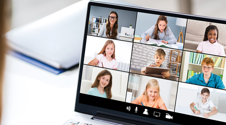 Teacher using laptop at desk video call with students
