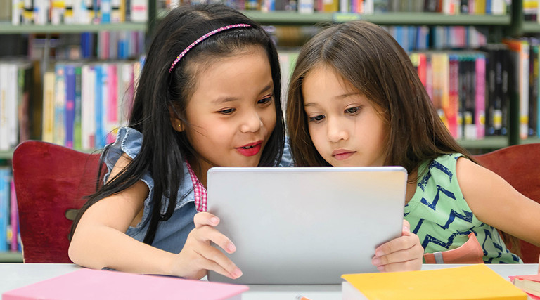 Two girls using tablet for remote learning