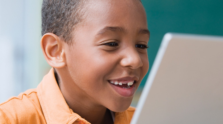Boy smiling looking at his computer. 