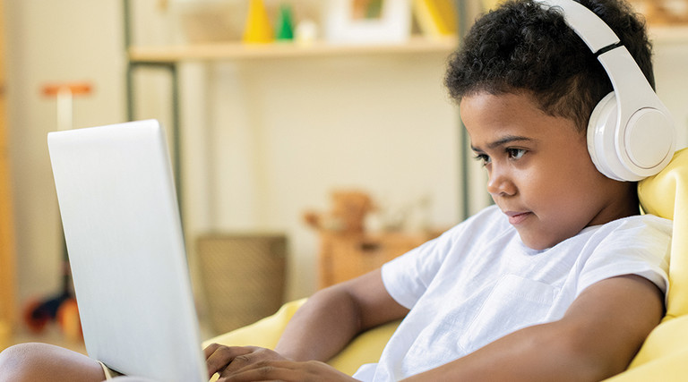Boy with headphones looking at computer screen 