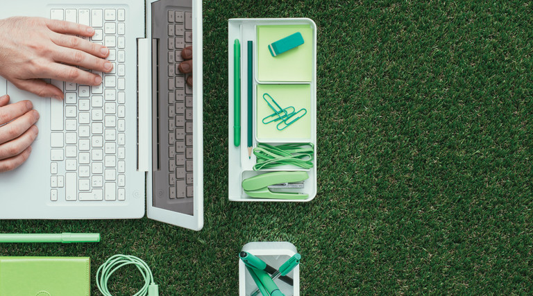 Tech sustainability concept, laptop and office supplies on grass