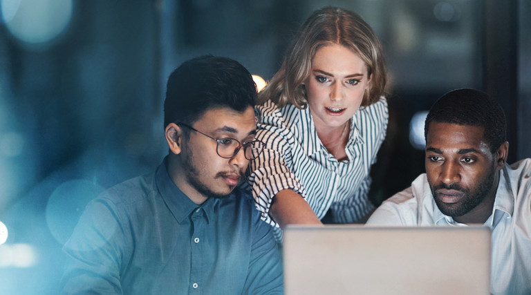 Three people looking at a laptop screen.