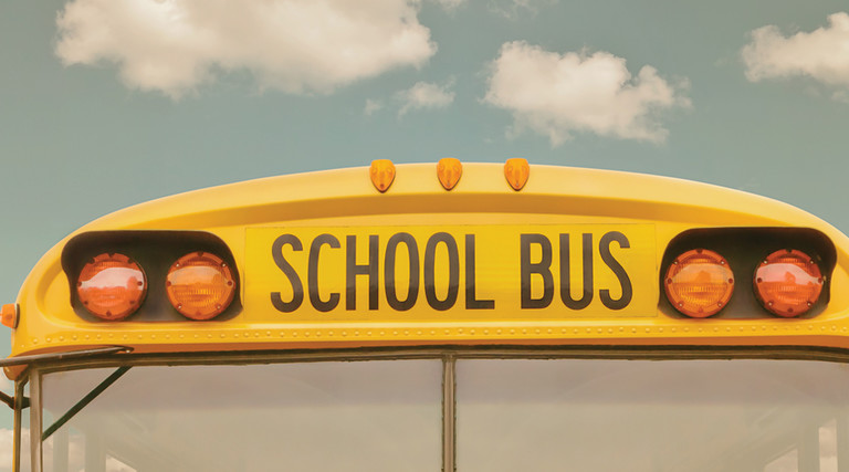 The front of a school bus against a cloudy sky