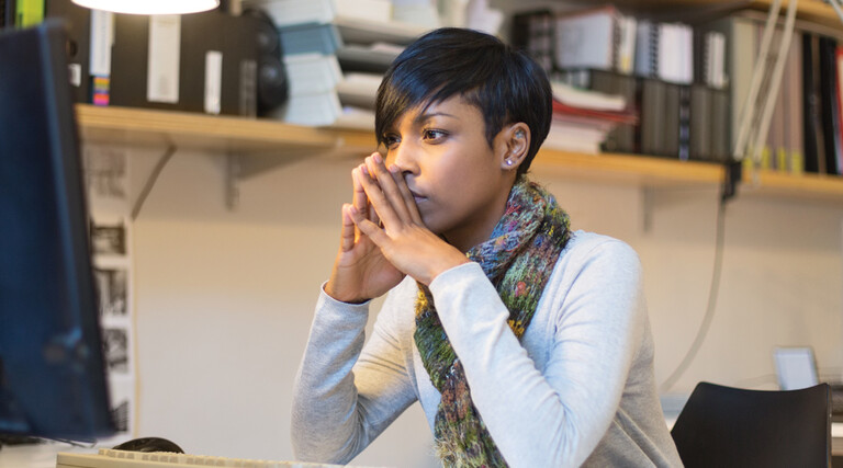IT person mulling over information while sitting at desktop computer