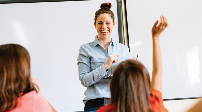 A teacher in the front of a classroom teaching students.