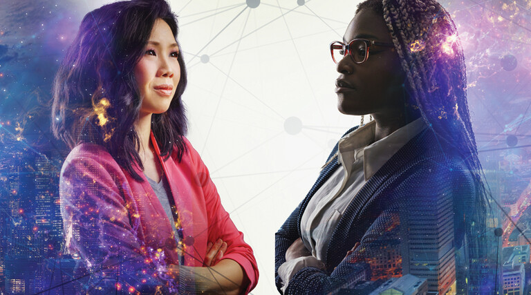 Image shows two women looking at each other with their arms crossed and a cityscape behind them