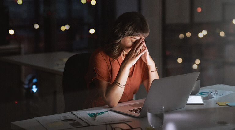 Woman sitting in front of a laptop looking concerned late at night