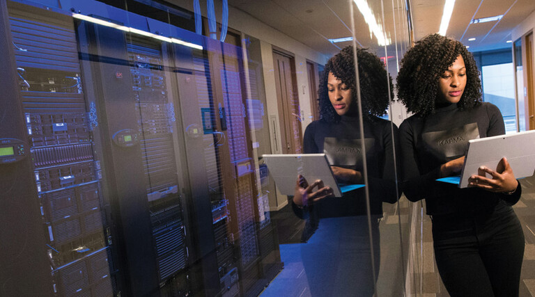 IT leader using a laptop computer next to servers