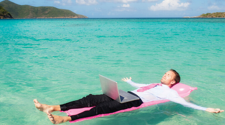 Person floating in the ocean while working on a computer