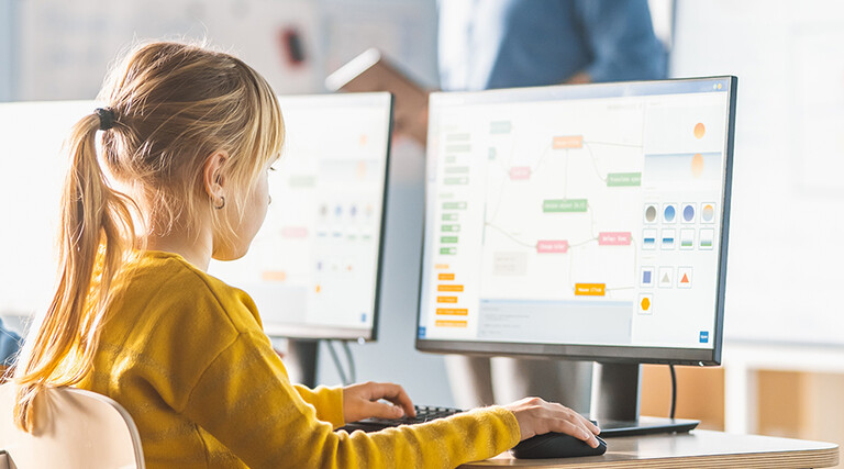 Kids in a classroom viewing the same information on their own monitors.