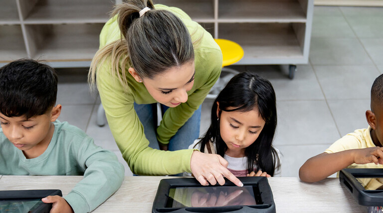 Teacher helping students using tablets