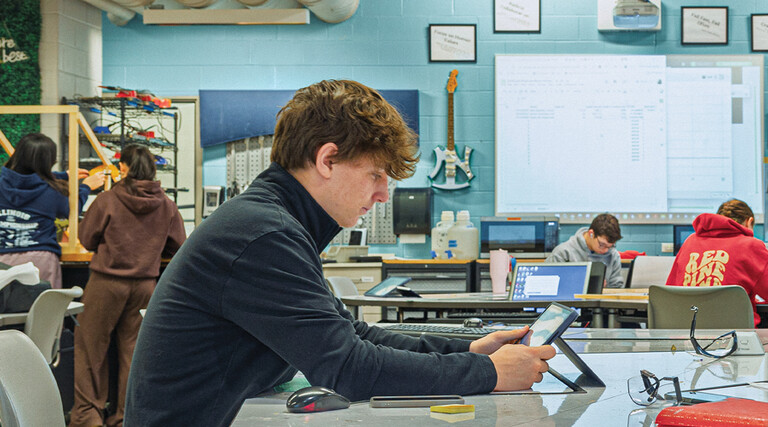 Student in a classroom working on a tablet at a table