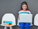 girl in row of chairs on laptop