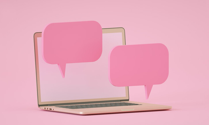 computer against pink backdrop with floating pink speech bubbles to indicate chatroom