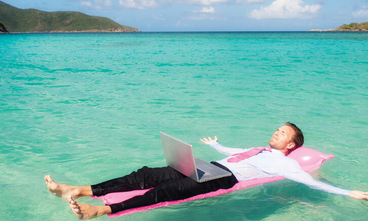 Person floating in the ocean while working on a computer