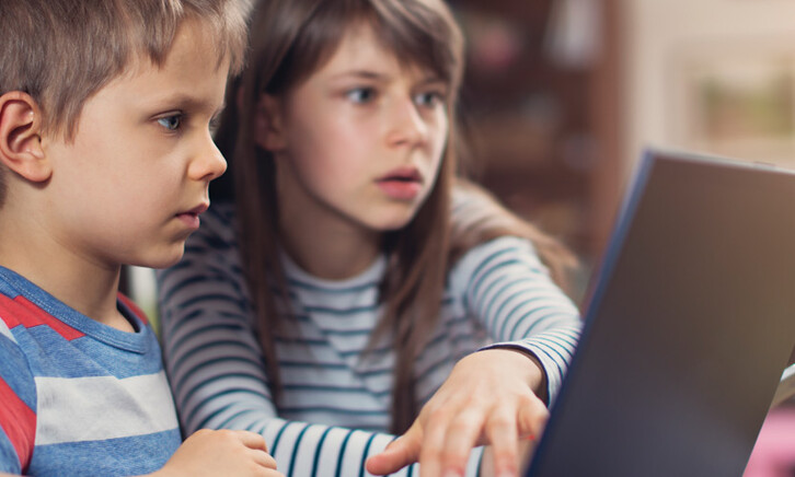 Two K–12 students working on a school laptop together