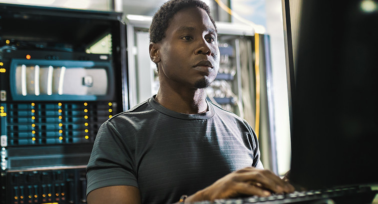 system admin man working in data center with laptop