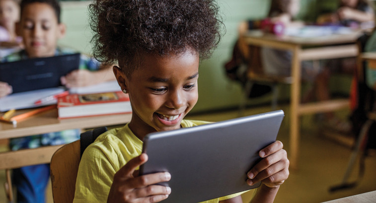 K-12 student using mobile tablet device in modern classroom