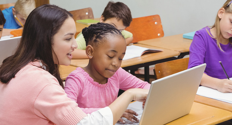 Teacher assisting student with laptop