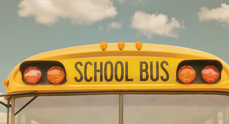 The front of a school bus against a cloudy sky