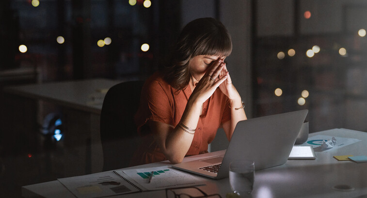 Woman sitting in front of a laptop looking concerned late at night