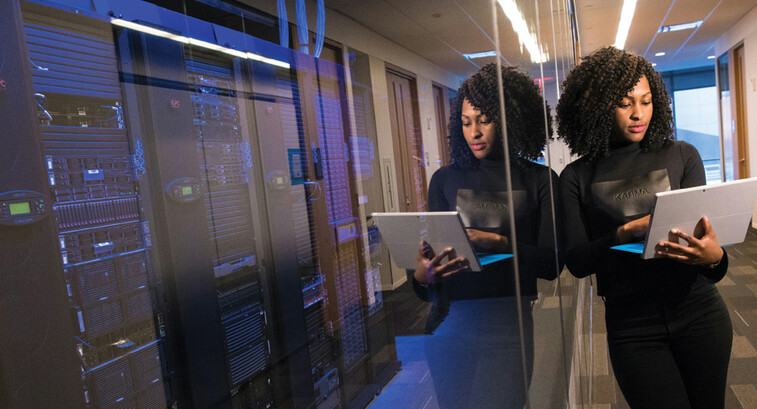 IT leader using a laptop computer next to servers