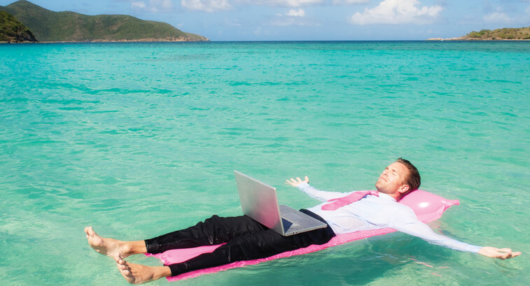 Person floating in the ocean while working on a computer