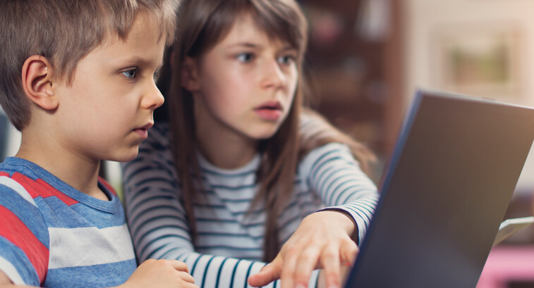 Two K–12 students working on a school laptop together