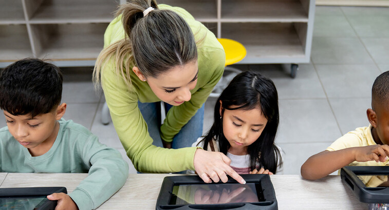 Teacher helping students using tablets