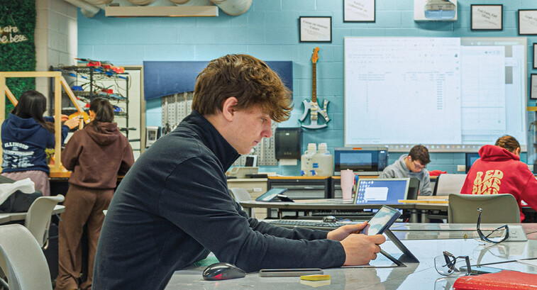 Student in a classroom working on a tablet at a table