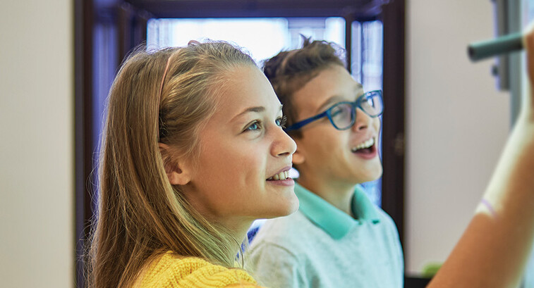 students smiling while writing on digital whiteboard
