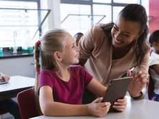 K-12 classroom teacher helping student with tablet
